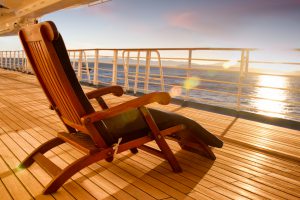 A wooden deck chair is placed upon the wooden deck